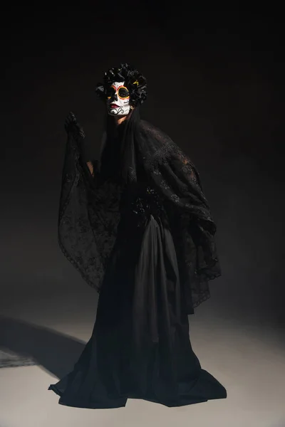 Full length of woman in traditional day of dead costume and catrina makeup posing on black background — Stock Photo