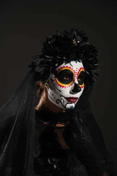 Femme en costume sombre d'Halloween et maquillage du crâne de sucre regardant loin isolé sur noir — Photo de stock