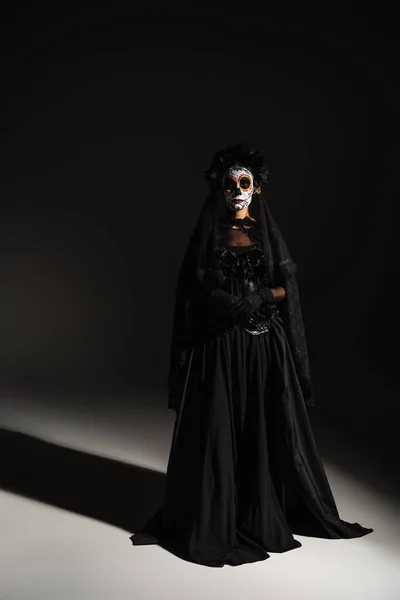 Full length of woman in mexican day of dead costume and spooky makeup on black background — Stock Photo