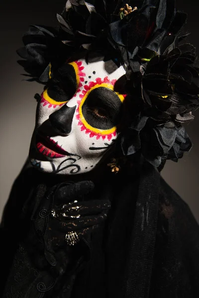 Portrait of woman in santa muerte makeup and black wreath on dark background — Stock Photo