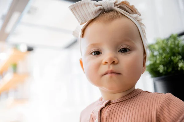 Portrait de bébé fille en bas âge dans le bandeau avec arc et robe rose regardant la caméra — Photo de stock