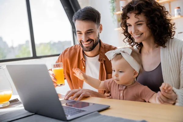 Famiglia felice con bambino piccolo che ha videochiamata sul computer portatile a casa — Foto stock