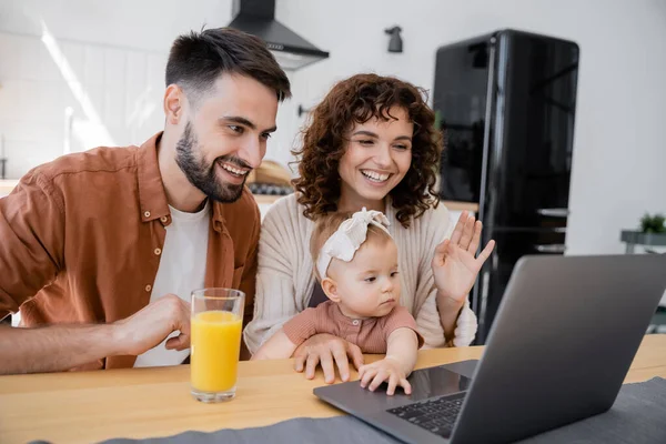 Cheerful family with infant child having video call on laptop at home — Stock Photo