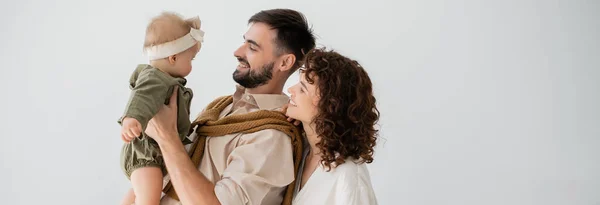 Cheerful young father holding in arms infant daughter near curly wife, banner — Stock Photo