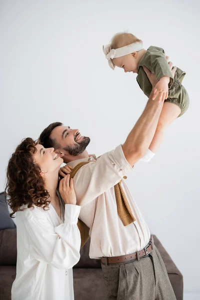 Fröhlicher junger Vater hält kleine Tochter in den Armen neben glücklicher Frau — Stockfoto