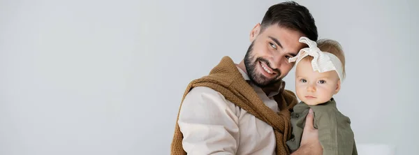 Cheerful bearded father holding in arms infant girl in dress and headband, banner — Stock Photo