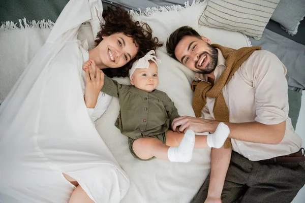 Vista superior de pais felizes e bebê menina deitada na cama em casa — Fotografia de Stock