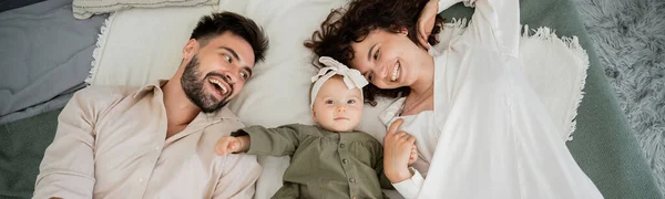 Vue du haut des parents heureux et bébé fille couché sur le lit à la maison, bannière — Photo de stock