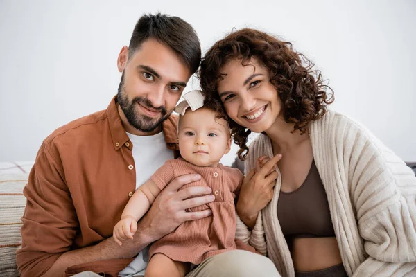 Retrato de padre alegre sosteniendo hija bebé feliz cerca de esposa sonriente - foto de stock