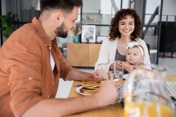 Bärtiger Mann frühstückt mit glücklicher Frau und kleiner Tochter — Stockfoto