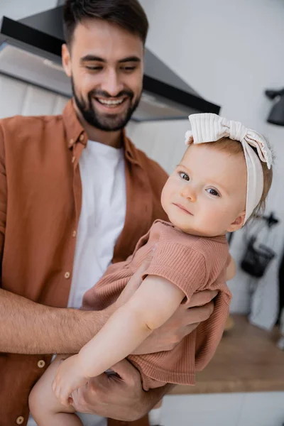 Щасливий чоловік з бородою тримає в руках дитячу дочку в пов'язці — стокове фото