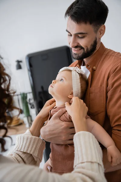 Felice padre barbuto in braccio bambino figlia vicino moglie a casa — Foto stock