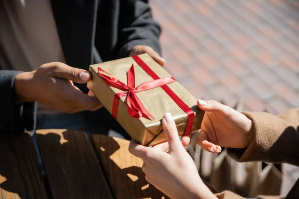 Vista parcial del hombre afroamericano dando regalo de año nuevo a la mujer al aire libre - foto de stock