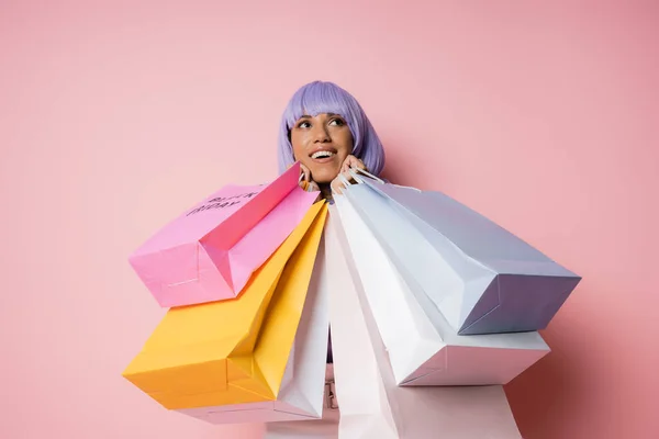 Mulher americana africana espantado com cabelo roxo segurando sacos de compras com letras sexta-feira preta em rosa — Fotografia de Stock