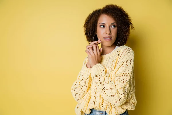 Curiosa e giovane donna afroamericana in maglione lavorato a maglia distogliendo lo sguardo sul giallo — Foto stock