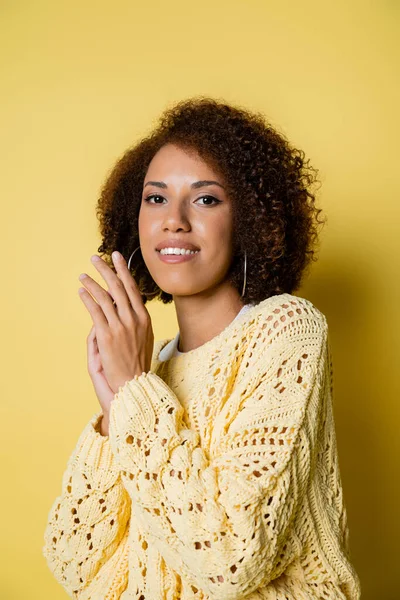 Smiling and young african american woman in knitted sweater on yellow — Stock Photo