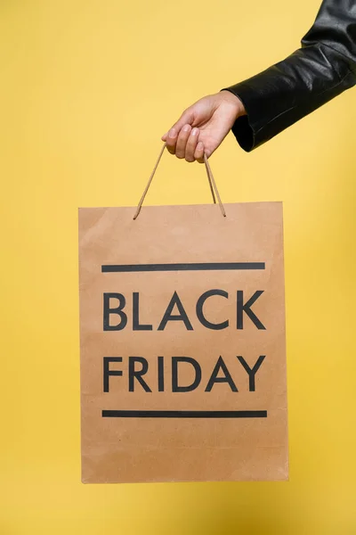 Vista cortada da mulher americana africana segurando saco de compras sexta-feira preto no amarelo — Fotografia de Stock