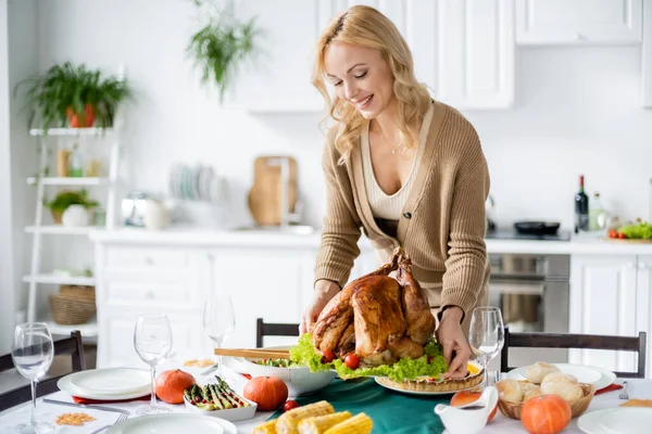 Lächelnde Frau stellt Erntedank-Truthahn auf heimischen Tisch — Stockfoto