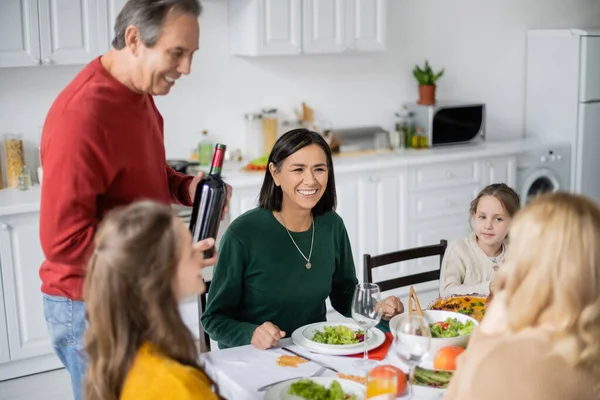 Multiethnische Frau sitzt neben Familie und leckeres Dankessen in der Küche — Stockfoto