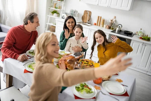 Allegro famiglia interrazziale mani agitando durante selfie e cena di ringraziamento a casa — Foto stock