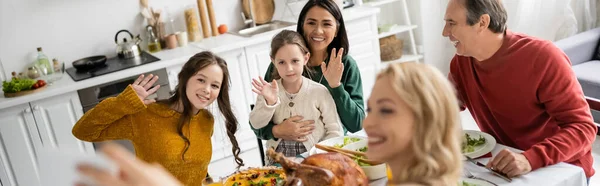 Famille multiculturelle souriante prenant selfie pendant Thanksgiving à la maison, bannière — Photo de stock