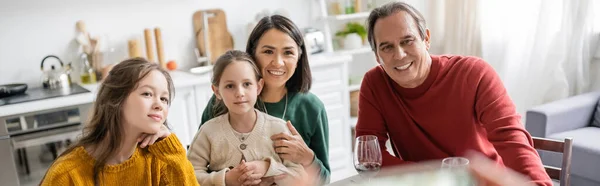 Sonrientes abuelos y nietos interraciales mirando hacia otro lado durante la celebración de Acción de Gracias en casa, pancarta - foto de stock