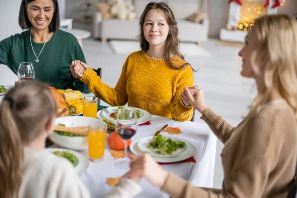 Adolescente sorridente che si tiene per mano della famiglia multietnica vicino alla cena del Ringraziamento a casa — Stock Photo