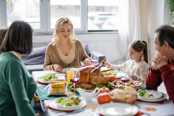 Positive woman sitting near parents and children during thanksgiving dinner at home — Stock Photo