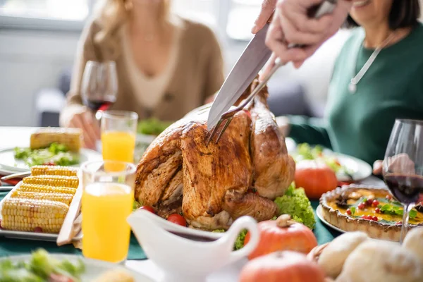 Обрезанный вид человека, режущего вкусную индейку во время ужина в честь Дня благодарения дома — стоковое фото
