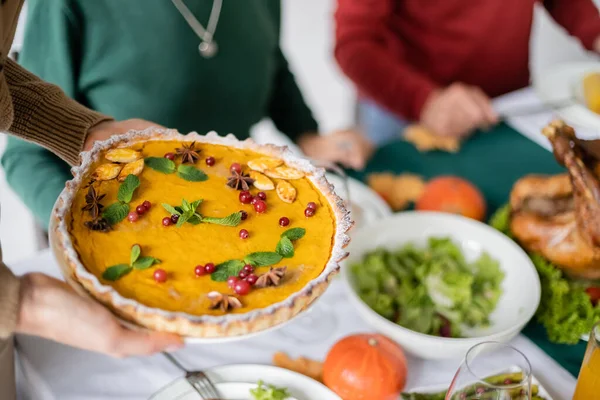 Cropped view of woman holding thanksgiving pie during thanksgiving dinner — Stock Photo