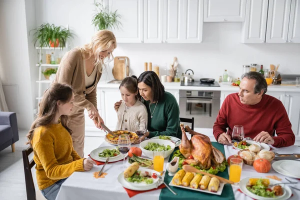 Família inter-racial olhando para torta de ação de graças durante o jantar festivo em casa — Fotografia de Stock