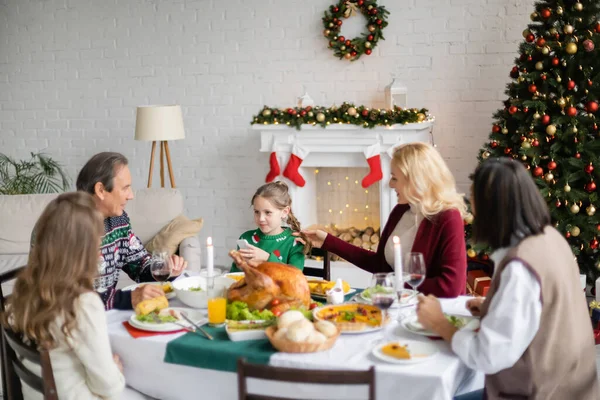 Mulher tocando o cabelo da filha perto de família multiétnica ter jantar de Natal — Fotografia de Stock