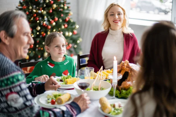 Fröhliche Frau schaut Familie beim festlichen Abendessen am Weihnachtsbaum an — Stockfoto