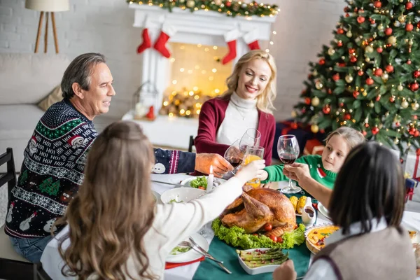 Cheerful interracial family clinking glasses near delicious roasted turkey on christmas dinner at home — Stock Photo