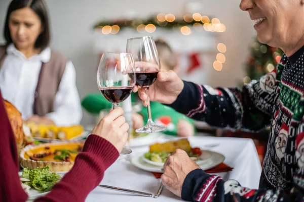 Sonriente hombre tintineo copas de vino con hija durante la cena festiva de acción de gracias - foto de stock