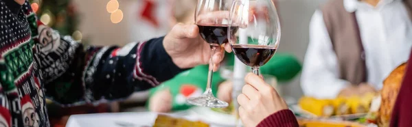 Vista recortada del hombre mayor con la hija adulta tintineo vasos de vino tinto durante la cena de acción de gracias, bandera - foto de stock