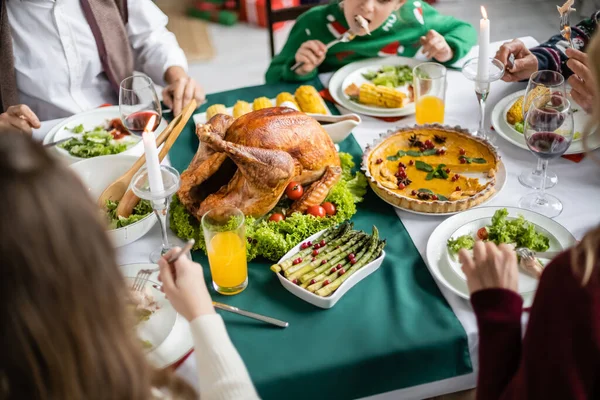 Vista cortada da família perto de delicioso peru assado e torta de abóbora servida para o jantar festivo de ação de graças — Fotografia de Stock