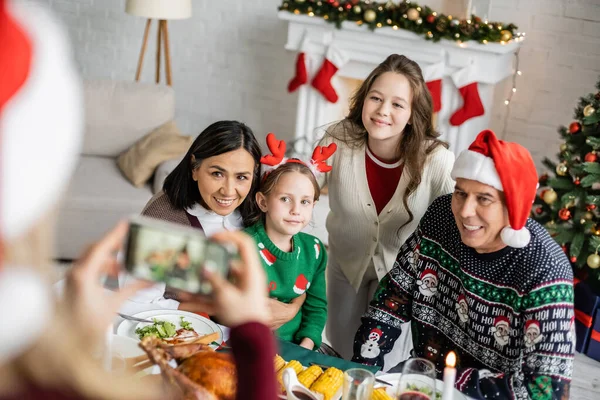 Blurred woman taking photo of daughters with interracial grandparents near festive dinner — Stock Photo