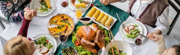 Vista superior de la familia tomados de la mano y rezando cerca de deliciosa cena de acción de gracias, pancarta - foto de stock