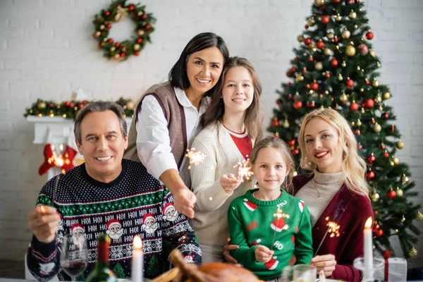 Alegre família multiétnica segurando brilhos durante a celebração do Natal — Fotografia de Stock