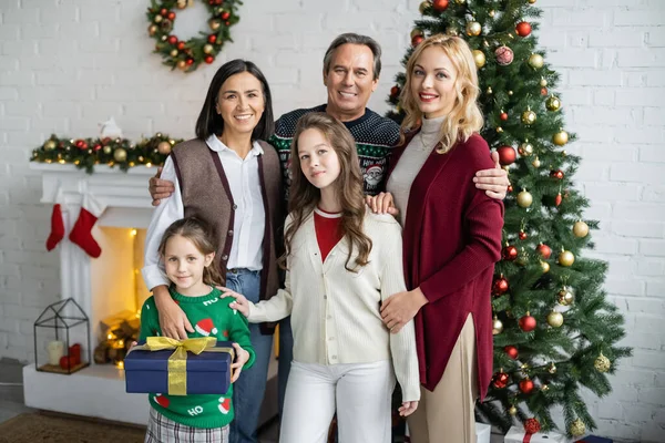 Sorelline felici con nonni e madre interrazziali che guardano la fotocamera in soggiorno con decorazioni natalizie — Foto stock