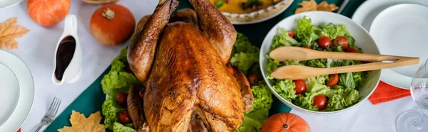 Top view of tasty roasted turkey near fresh vegetable salad and sauceboat served for thanksgiving dinner, banner — Stock Photo