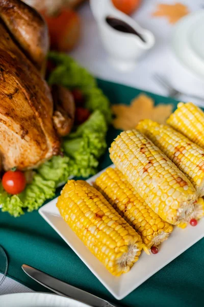 Вид сверху на жареную кукурузу рядом с вкусной жареной индейкой, подаваемой на ужин в честь Дня благодарения — стоковое фото