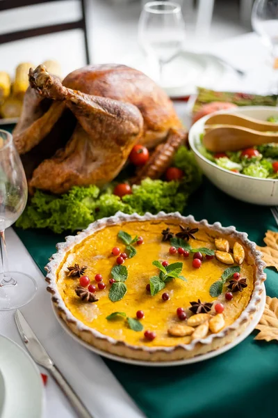 Традиційний гарбузовий пиріг з журавлиною біля смаженої індички та свіжим овочевим салатом, який подається на вечерю подяки — стокове фото