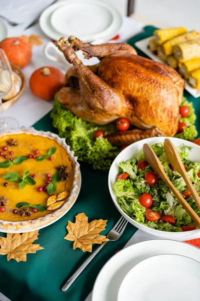 Vista de ángulo alto de pavo asado cerca de ensalada de verduras frescas y pastel de calabaza con arándanos - foto de stock