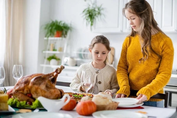 Sisters near table served with delicious turkey and traditional pumpkin pie for thanksgiving dinner — Stock Photo