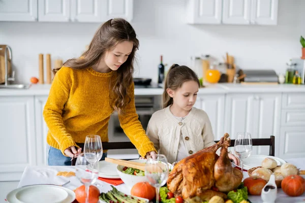 Kids serving table for festive thanksgiving dinner near roasted turkey and vegetables — Stock Photo