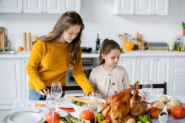 Table de service pour enfants pour le dîner festif d'Action de grâces près de dinde rôtie et légumes — Photo de stock