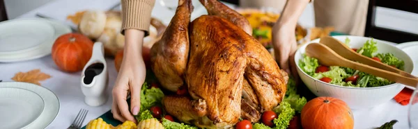 Cropped view of woman serving roasted turkey near fresh vegetable salad for thanksgiving dinner, banner — Stock Photo