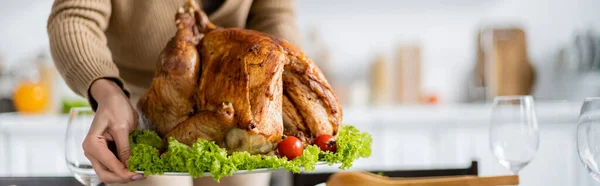 Vista parcial de la mujer sosteniendo pavo tradicional de acción de gracias con verduras frescas, pancarta - foto de stock